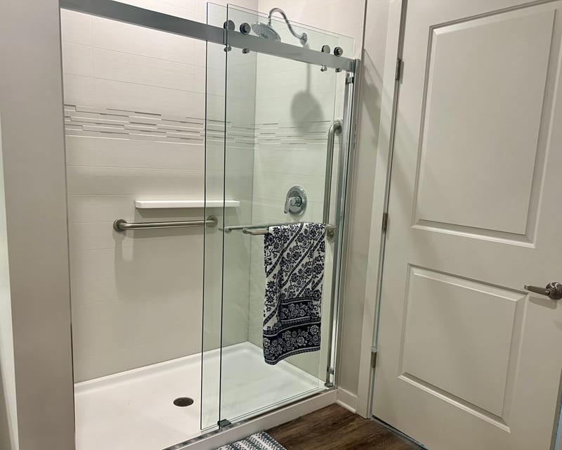 Glass-enclosed stand-up shower with grab bars