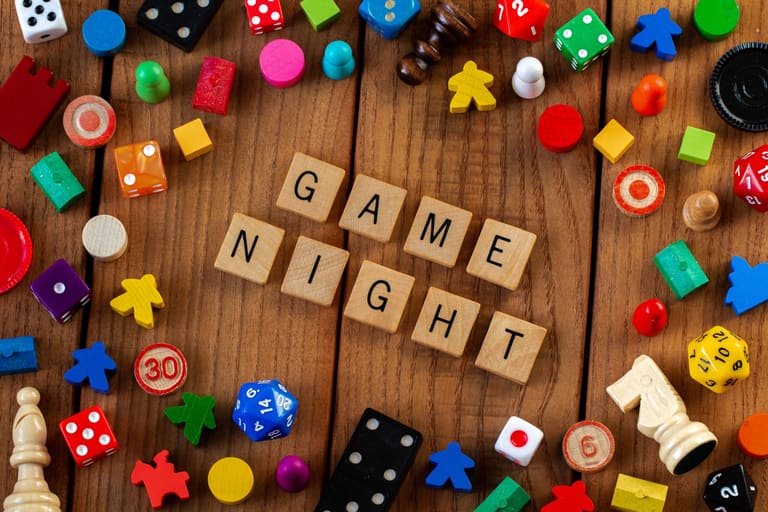 Board game pieces and dice surrounding the words Game Night