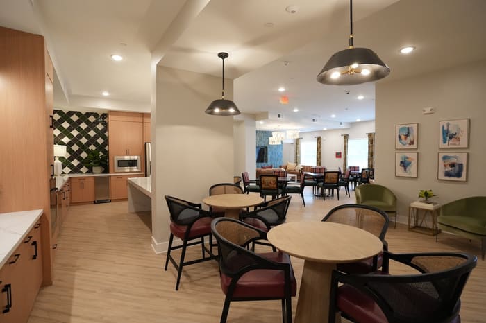 Clubroom dining tables beside the kitchen and lounge