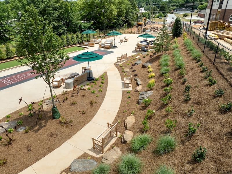 Landscaped courtyard with paths, seating, shuffleboard, and putting green