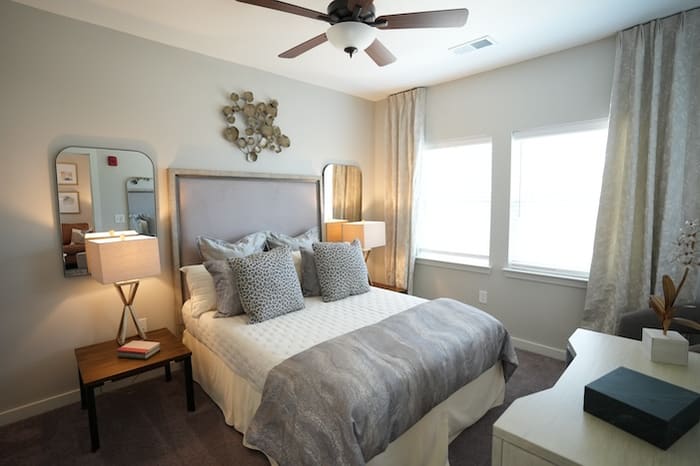 Bedroom in a one-bedroom apartment at Park Place by Highlands furnished with a queen bed, bedside tables and a ceiling fan