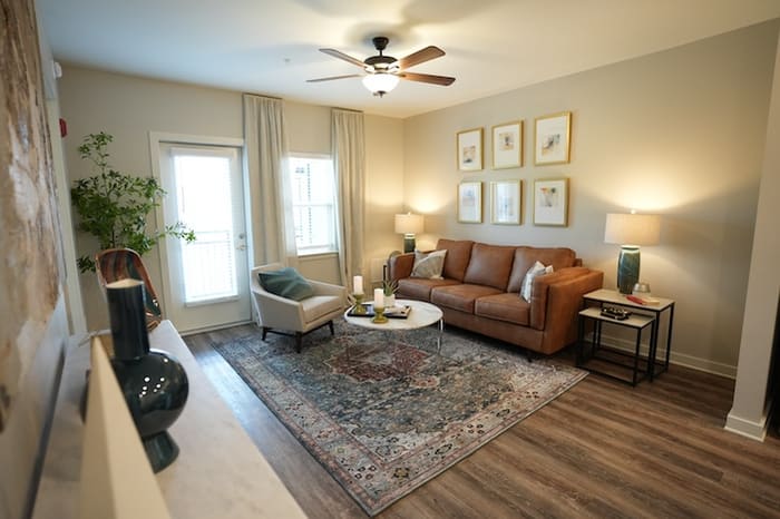 Furnished living area in a one-bedroom apartment at Park Place by Highlands with a ceiling fan and a glass door onto the balcony