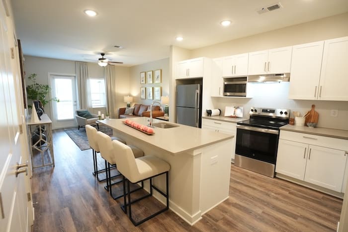 Open-plan kitchen, dining and living area in the Avonlea one-bedroom at Park Place by Highlands, with a quartz island and bar seating